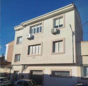 a white building with windows and a car parked in front at Apartamento Pinilla Lagunas de Villafáfila in Manganeses de la Lampreana