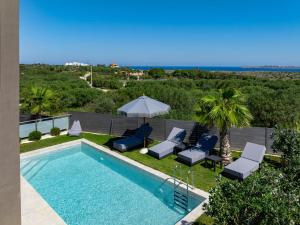 a swimming pool with lounge chairs and an umbrella at FOGE luxury villa Agios Onoufrios in Chania