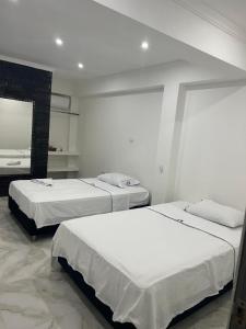 two beds in a room with white walls at Hotel Pacífico Azul in Bahía Solano