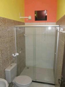 a bathroom with a toilet and a glass shower at Pousada Oritibe in Cairu