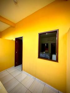 a room with a yellow wall with a mirror at Pousada Oritibe in Cairu