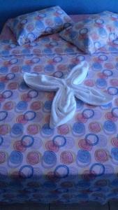 a white cross on a bed with pink and blue cupcakes at Pousada Oritibe in Cairu