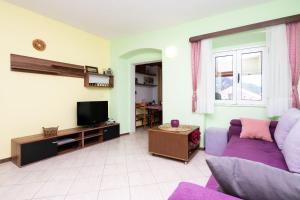 a living room with a purple couch and a tv at Apartment Bezerusa in Igrane