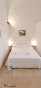 a white bed in a white room with two lamps at Domus Avi - Bed and Breakfast in Taviano