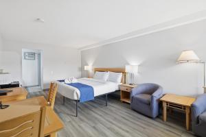 a hotel room with a bed and a chair and a desk at Canada's Best Value Desert Inn & Suites in Cache Creek