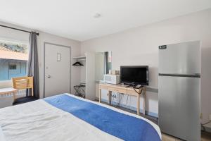 a bedroom with a bed and a refrigerator and a television at Canada's Best Value Desert Inn & Suites in Cache Creek