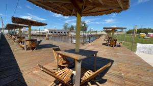 a wooden deck with tables and chairs and an umbrella at Mini Fazenda Park in Santana do Livramento