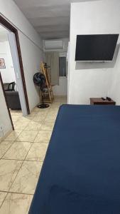 a bedroom with a blue bed and a tv on the wall at Ótimo Quarto e Sala mobiliado em itapoa. in Vila Velha