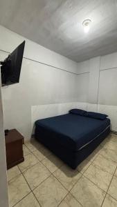 a bedroom with a blue bed and a tv at Ótimo Quarto e Sala mobiliado em itapoa. in Vila Velha