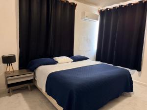a bedroom with a bed with blue sheets and a window at Departamento completo bien ubicado in Minatitlán