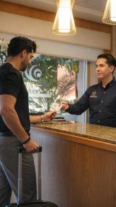 due uomini in piedi a un bar con un uomo che porge una ricevuta di Hotel Zafra a Torreón