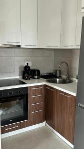a kitchen with white cabinets and a sink and a stove at SiM Lux in Čačak