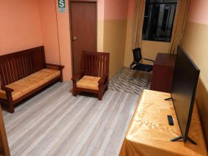 a room with two beds and a table with a television at Nery Lodging in Huaraz
