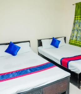 zwei Betten mit blauen Kissen, die nebeneinander stehen in der Unterkunft Hotel Asad in Mymensingh