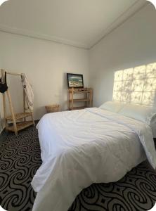 a bedroom with a white bed and a window at White House TAMRAGHT in Agadir