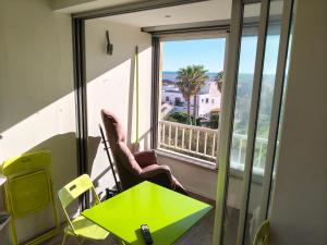 a room with a table and a green table and a window at Beach 50 m , vue mer in Carnon-Plage