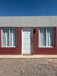 a red building with a white door and two windows at Cabañas boutique la soñada BIS in Fiambalá