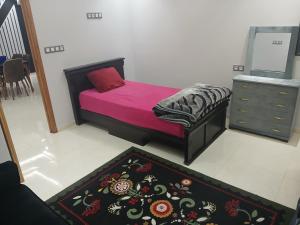 a bedroom with a bed and a dresser and a rug at تجزئة الفتح 925 خريبكة 3 in Khouribga