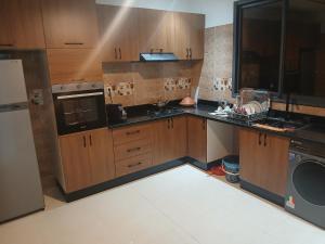 a large kitchen with wooden cabinets and a refrigerator at تجزئة الفتح 925 خريبكة 3 in Khouribga