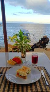a white plate with a sandwich on a table with the ocean at Bunaken Paradise Beach Homestay in Bunaken