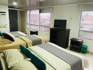a room with three beds and a flat screen tv at Hotel Colonial Betulia D in Tunja