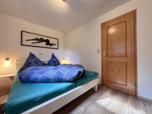 a bedroom with a bed with blue pillows and a door at Haus Anna in Stadlern