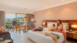 a woman and child sitting on a bed in a hotel room at Royal Solaris Los Cabos - All Inclusive in San José del Cabo