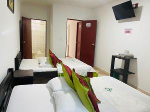 a room with three beds and a tv on the wall at Hotel Colonial El Bosque A in Tunja