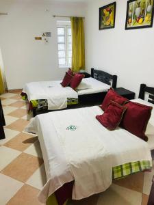 a room with three beds with white and red pillows at Hotel Colonial El Bosque A in Tunja
