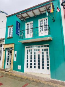 a green building with white doors and a balcony at Hotel Colonial El Bosque A in Tunja