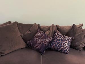 a brown couch with four pillows on it at Woonhuis 170m2 Rotterdam Centrum in Rotterdam