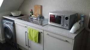 a kitchen counter with a microwave and a sink at Central Aberdeen Apartment in Aberdeen