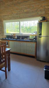 a kitchen with a stainless steel refrigerator and a table at CASA GRÊS - Pousada Vale das Escarpas in Timbe do Sul +1 photo