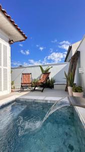 a swimming pool with two chairs next to a house at A Casinha de Madeira in Balneário Gaivotas