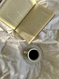 an open book and a cup of coffee on a bed at A Casinha de Madeira in Balneário Gaivotas