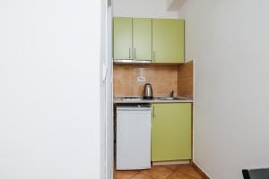 a small kitchen with green cabinets and a sink at Apartments Nada in Petrovac na Moru