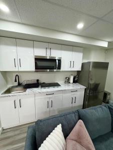 a kitchen with white cabinets and a blue couch at Velvet and Rose Elegant Private 2BR Basement Suite in Winnipeg