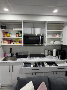 a kitchen with a sink and a microwave at Velvet and Rose Elegant Private 2BR Basement Suite in Winnipeg +22 photos
