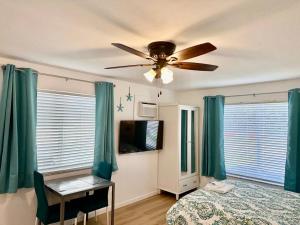 a bedroom with green curtains and a ceiling fan at Seashell 5 in Boynton Beach
