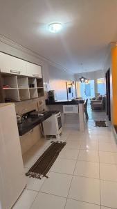 a kitchen with white cabinets and a living room at Cantinho Acolhedor com 4 cama e 2 quartos in Juazeiro do Norte