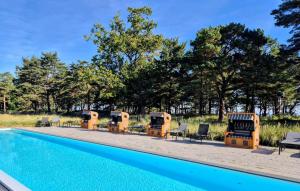 a swimming pool with chairs and tables and trees at Baltic in Binz
