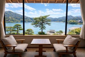a room with two chairs and a table and a large window at 碧翠御苑 ゲストハウス風月庵 in Kyotango