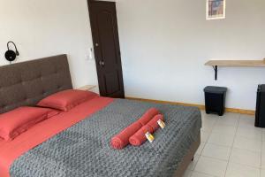 a bedroom with a bed with two red pillows at TIARE - City center room Papeete in Papeete