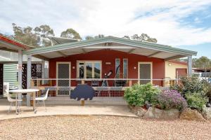 a red house with a table and a chair at L'Air du Wombat Truffle Farm in Corang