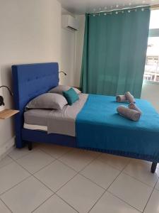 a blue bed in a room with a window at DREAMLINER - City center room Papeete in Papeete