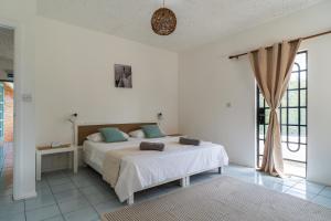 a white bedroom with a bed and a window at Mont Choisy Lodge 7 Rooms, Large Pool, 2 Min Walk to Beach in Grand-Baie