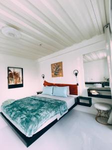 a white bedroom with a large bed and a chair at Bougainvillea guesthouse in San Juan