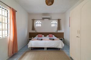 a bedroom with a bed with pink pillows on it at Mont Choisy Lodge 7 Rooms, Large Pool, 2 Min Walk to Beach in Grand-Baie