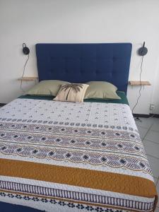 a bed with a blue headboard and pillows on it at HONEY - City center room Papeete in Papeete