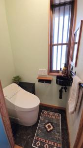 a bathroom with a toilet and a window and a rug at Cabin Dilusso in Hokuto +23 photos